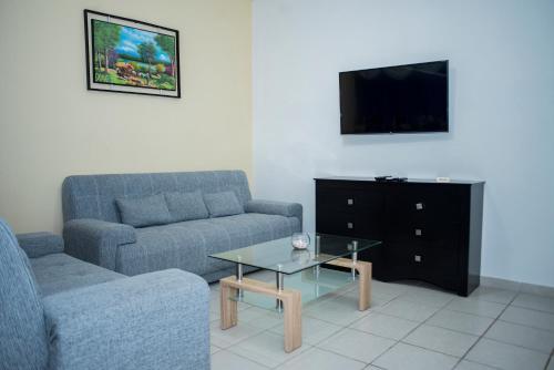 sala de estar con sofá, mesa y TV en La Estancia Apartments Mazatlan, en Mazatlán