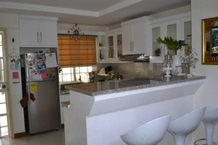 a kitchen with white cabinets and a counter with white stools at Fully Furnished Villa Near Clark in Mabiga, Mabalacat City in Mabalacat