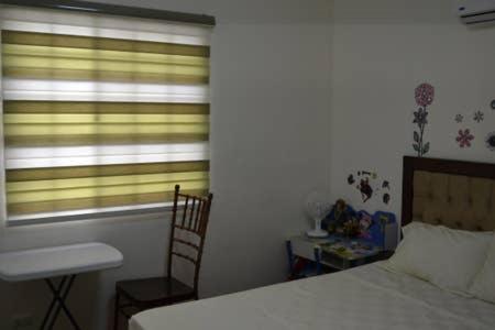 a bedroom with a bed and a window and a chair at Fully Furnished Villa Near Clark in Mabiga, Mabalacat City in Mabalacat