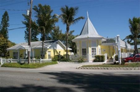 a yellow house with a white steeple and a church at Queens Gate Resort in Bradenton Beach
