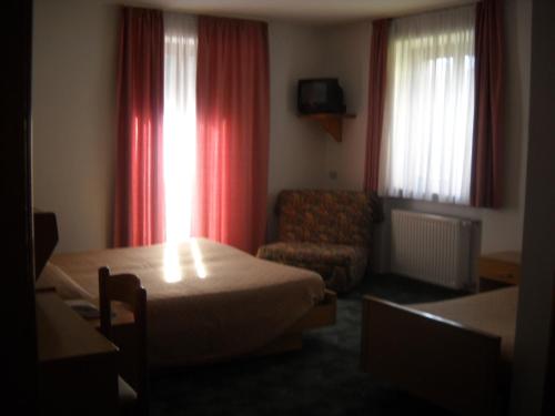 a hotel room with a bed and a chair at B&B Chiara- Alleghe in Alleghe