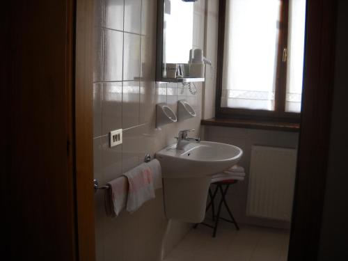 a white bathroom with a sink and a window at B&B Chiara- Alleghe in Alleghe