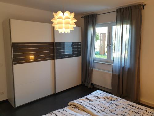 a bedroom with a bed and a window and a chandelier at Andinas Ferienwohnung in ruhiger Lage direkt am Wald in Wilnsdorf