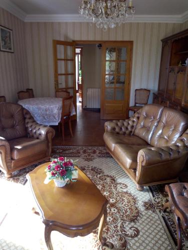 a living room with leather couches and a table at 1 Maison en pierre in Petreto-Bicchisano