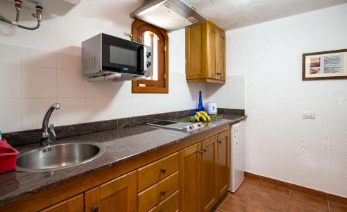 a kitchen with a sink and a tv on the wall at Casas rurales de Guayadeque in Ingenio