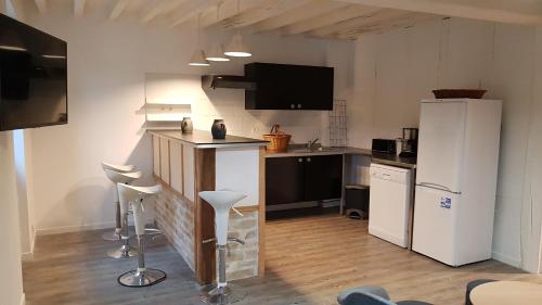 La cuisine est équipée d'un réfrigérateur et d'un comptoir avec tabourets. dans l'établissement L'Abaca 21, à Sainte-Geneviève-lès-Gasny