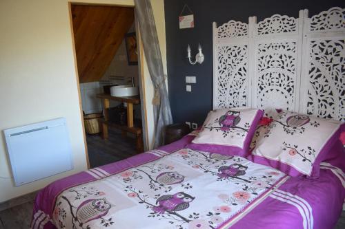 a bedroom with a bed with purple sheets and pillows at La mare aux Canards, 8mn du Zoo de Beauval in Châteauvieux