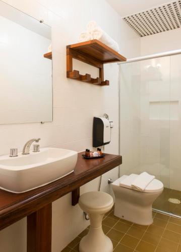 a bathroom with a sink and a toilet and a mirror at Hotel Porto Di Mare in Ubatuba