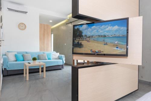 sala de estar con TV de pantalla plana en la pared en You and Me -750m from the sea en Kissamos
