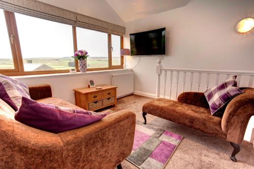 a living room with two chairs and a tv at Roman Height's Holiday Cottages in Haltwhistle