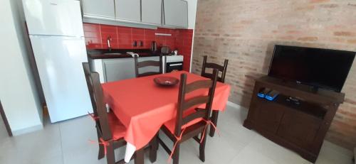une cuisine avec une table rouge, des chaises et une télévision dans l'établissement Los Cardenales, à Santa Ana