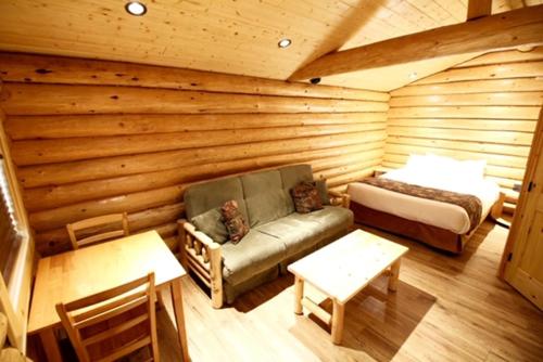 Habitación con cama y sofá en una cabaña de madera. en Port Hardy Cabins, en Port Hardy