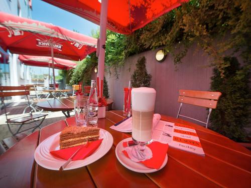 a wooden table with a slice of sandwich and a drink at Ramada Airport Hotel Prague in Prague