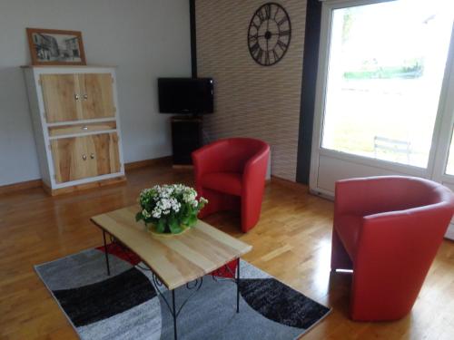 a living room with two red chairs and a table with flowers at GITE DES BOULEAUX in Maîche
