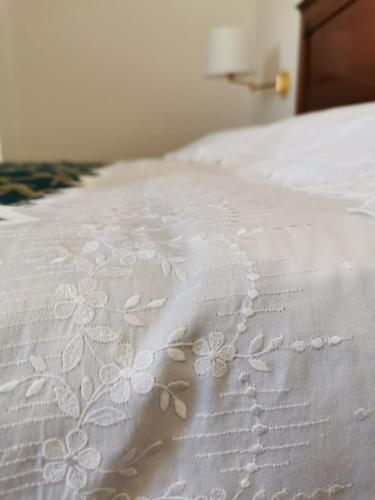 a white bed with white embroidered flowers on it at B&B Le Torri in Santeramo in Colle