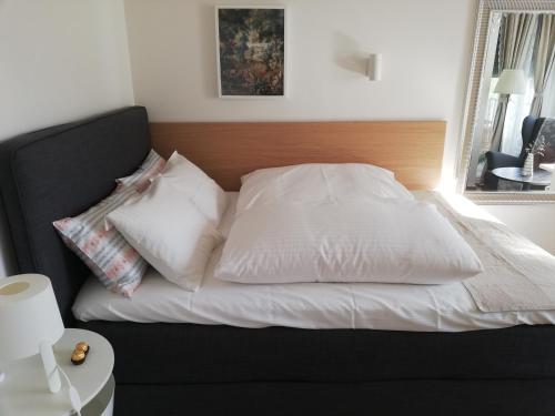 a bed with white sheets and pillows on it at Augarten Apartment in Graz
