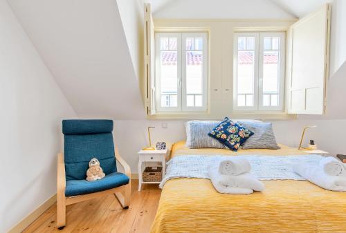 a bedroom with a bed and a blue chair at Casa do Sapalinho II - Setubal Downtown in Setúbal