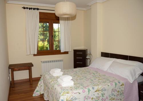 a bedroom with a bed with towels on it at Apartamentos El Retiro del Mirador by RetiroRural in Arenas de San Pedro