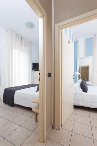 a hotel room with two beds and a doorway at Hotel Flora in Milano Marittima