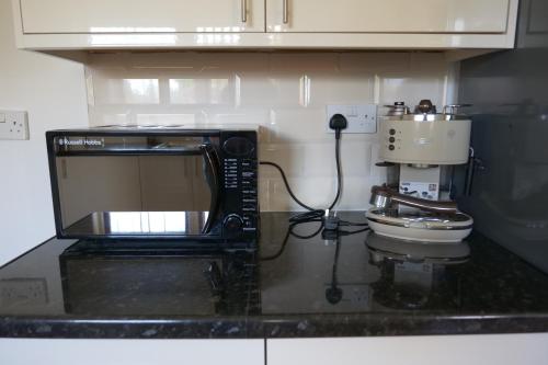 a kitchen counter with a microwave and a coffee maker at Kirkside Holiday Home in Alness