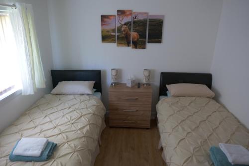 two beds sitting next to each other in a bedroom at Kirkside Holiday Home in Alness