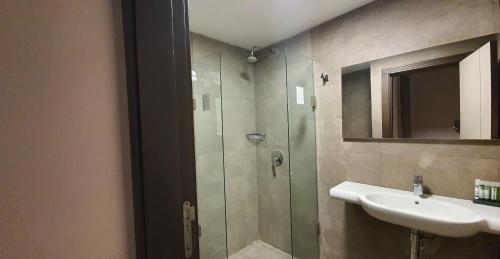Un baño con ducha de cristal y lavabo. en Grand Hotel Central Conakry, en Conakry