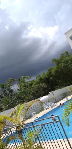 a swimming pool with chairs and trees in the background at Condomínio Conquista Premium Aleixo in Manaus