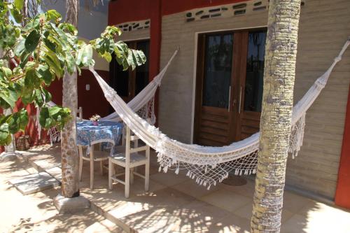 a hammock in front of a house with a table and chairs at Maria Teresa Bragança Pousada in Jericoacoara