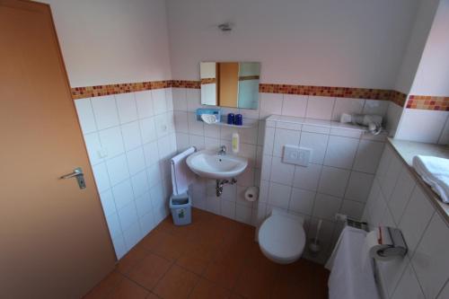 La petite salle de bains est pourvue de toilettes et d'un lavabo. dans l'établissement Hotel Landgasthof Zur Alten Scheune, à Zweibrücken
