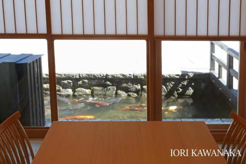 a table with a view of a pond through a window at IORI Stay HIDA in Hida