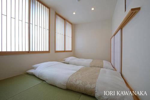 two beds in a room with two windows at IORI Stay HIDA in Hida