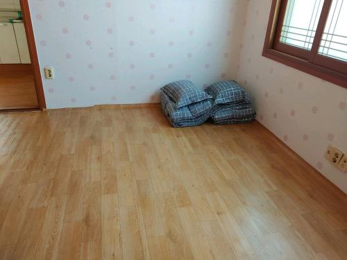 an empty room with two pillows on a wooden floor at Gimhae Guest House in Gimhae