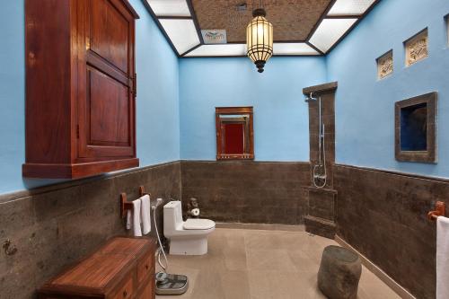 a bathroom with a toilet and blue walls at Villa Patria in Lovina
