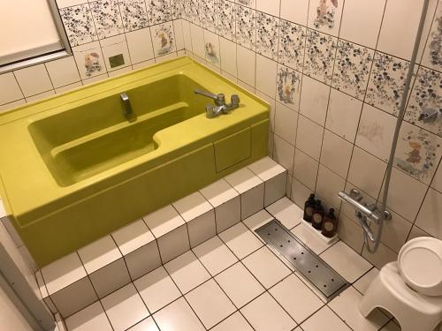 a bathroom with a green tub and a toilet at ビジネスインホテルプラザ21大阪京橋 in Osaka