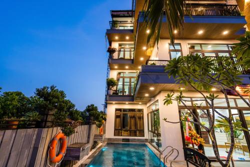 a house with a swimming pool in front of a building at Ancient River Villa in Hoi An