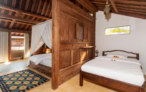 a bedroom with two beds in a room with wooden ceilings at Sun Suko Boutique Resort in Pemuteran