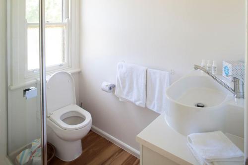a white bathroom with a toilet and a sink at Bird House in Kyneton