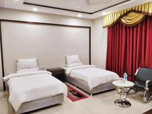 菩提伽耶Bodhgaya Seven Inn Hotel n Restaurant的红色窗帘间内的两张床