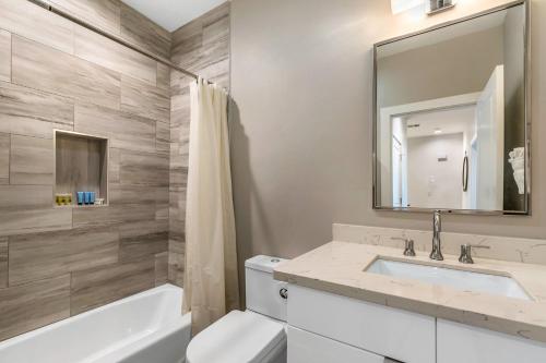 a bathroom with a sink and a toilet and a mirror at Bienville Villas: Brand New 4BR in New Orleans