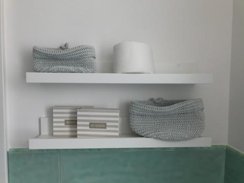 a white shelf with two baskets and books on it at IL CUCCO B&B in Ginosa Marina