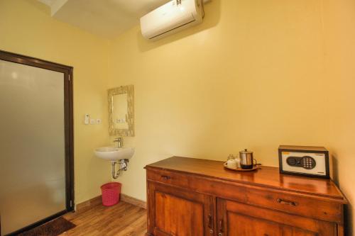 a bathroom with a sink and a wooden dresser at Pondok Kutuh Guest House in Ubud