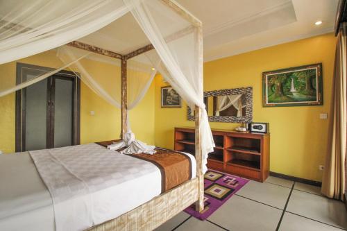 a bedroom with a canopy bed and a desk at Pondok Kutuh Guest House in Ubud