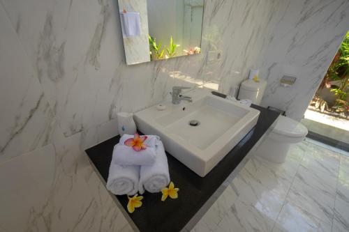a white bathroom with a sink and a towel at Juada Garden in Seminyak