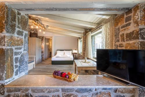 um quarto com uma parede de pedra, uma televisão e uma cama em Perachori Boutique Studios em Anogeia