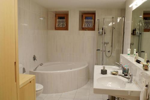ein Bad mit einer Badewanne, einem Waschbecken und einer Dusche in der Unterkunft Chasa Anna in Scuol