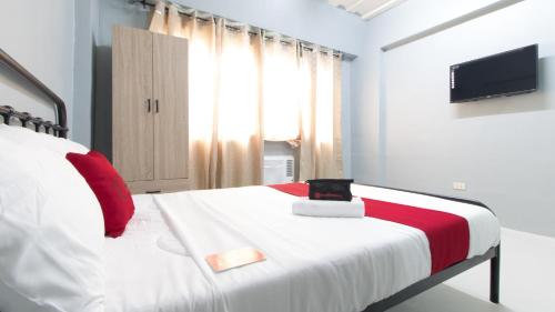 a bedroom with a white bed with red pillows at RedDoorz @ Sunfields Lipa Batangas in Lipa