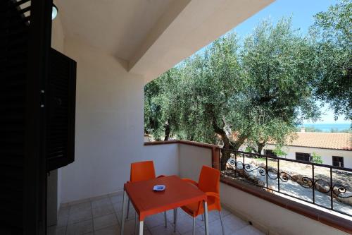 a balcony with a red table and chairs and a window at Zagare Residence in Rodi Garganico