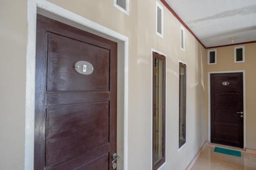 a wooden door in a hallway with two doors at RedDoorz Syariah near Mutiara SIS Al Jufrie Airport Palu 2 in Palu