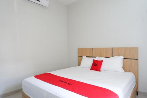 a bedroom with a bed with a red blanket on it at RedDoorz Syariah near Mutiara SIS Al Jufrie Airport Palu 2 in Palu