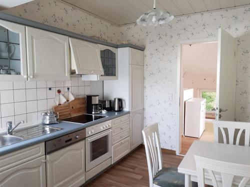 a kitchen with white cabinets and a sink and a table at Gartenblick in Oldenburg